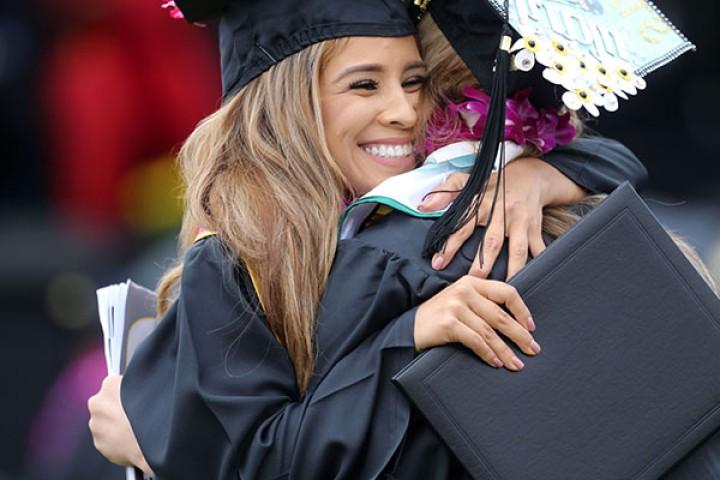 Graduates in caps and gowns hugging